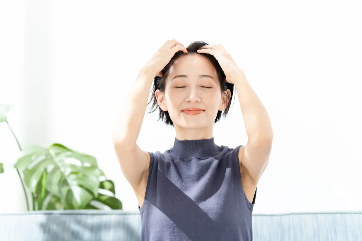髪を触るショートヘアの女性
