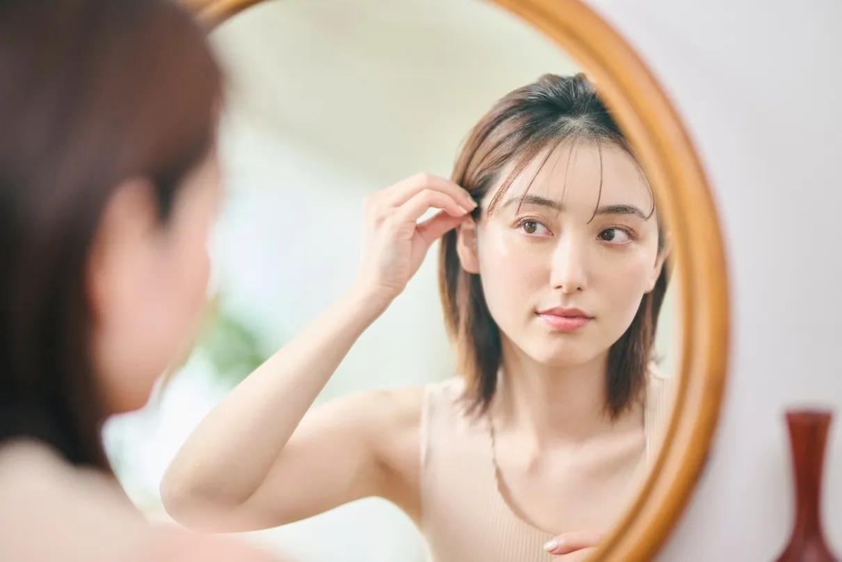 鏡を見ながら髪を整える女性
