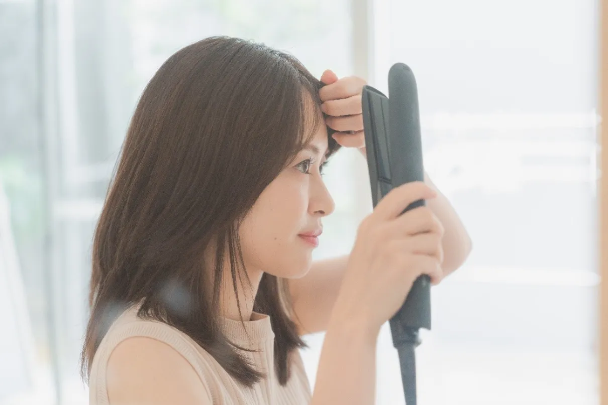 ヘアアイロンで前髪を整える女性
