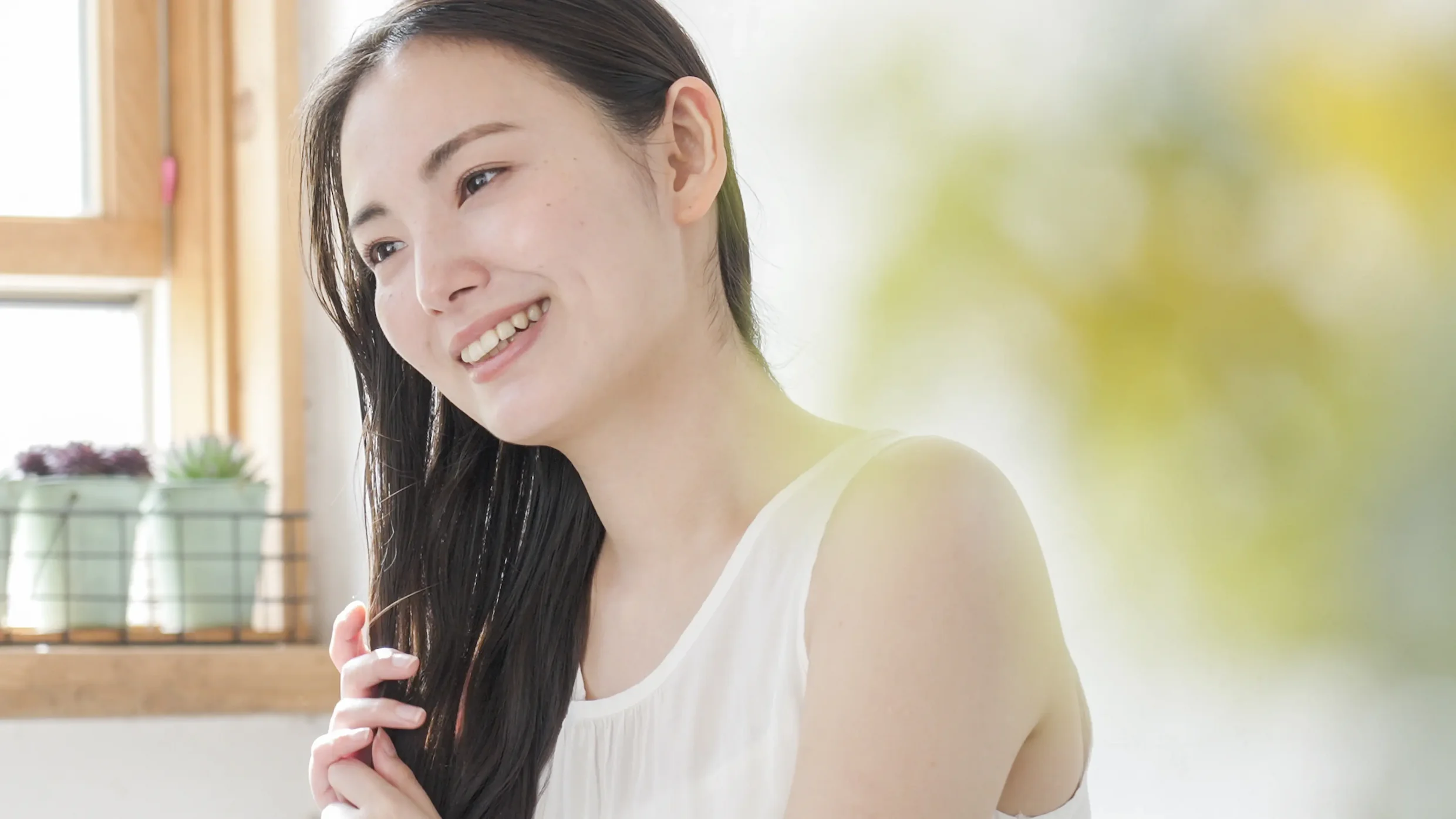 髪の毛を触りながら微笑む女性