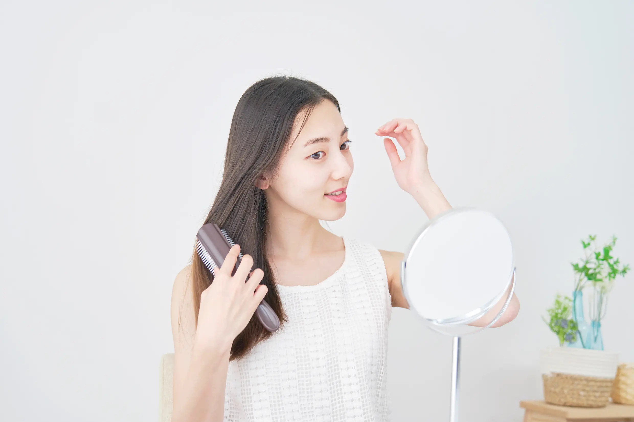 鏡を見ながらブラシで髪をとかす女性