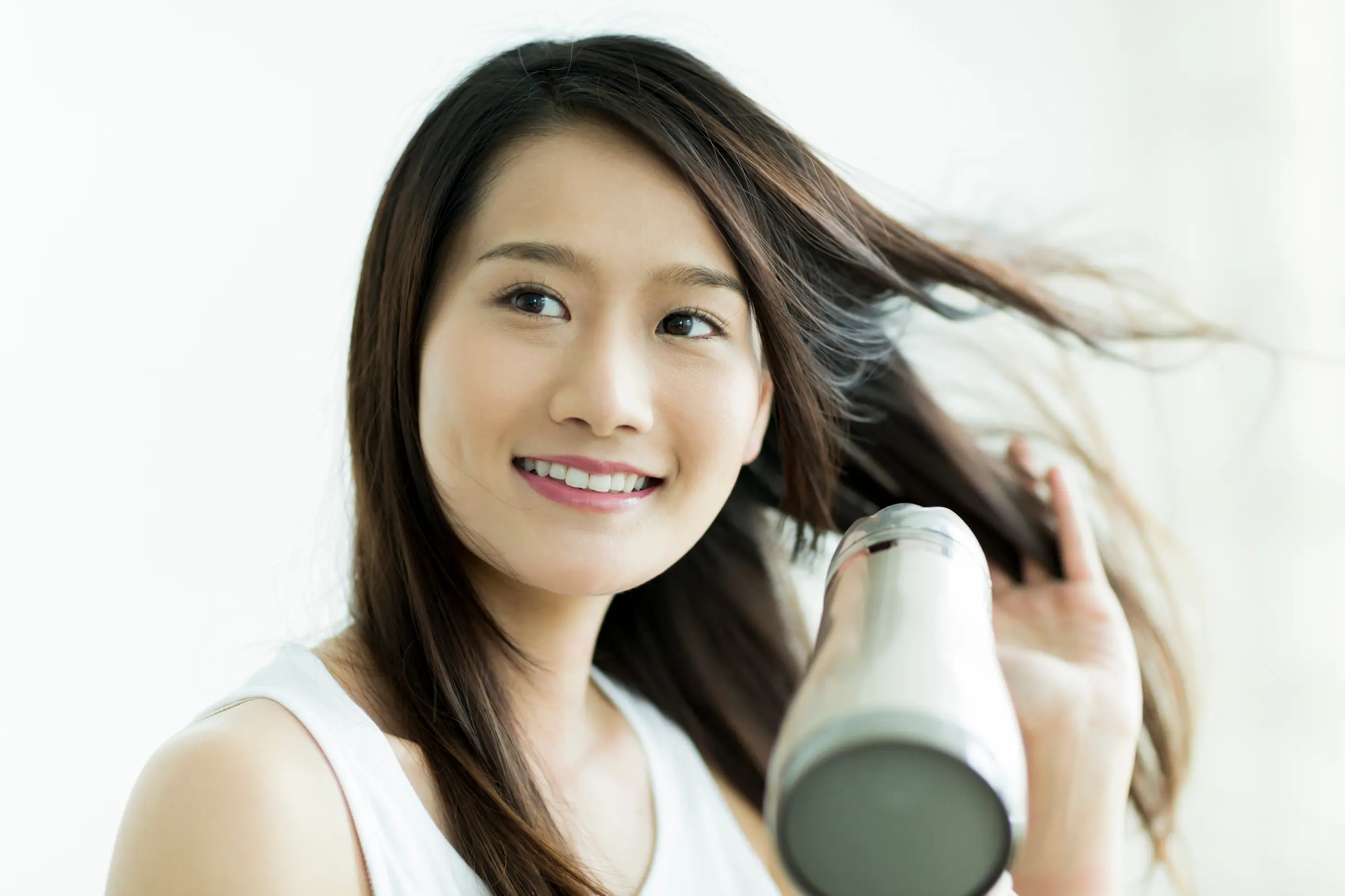ドライヤーで髪を乾かす女性の画像