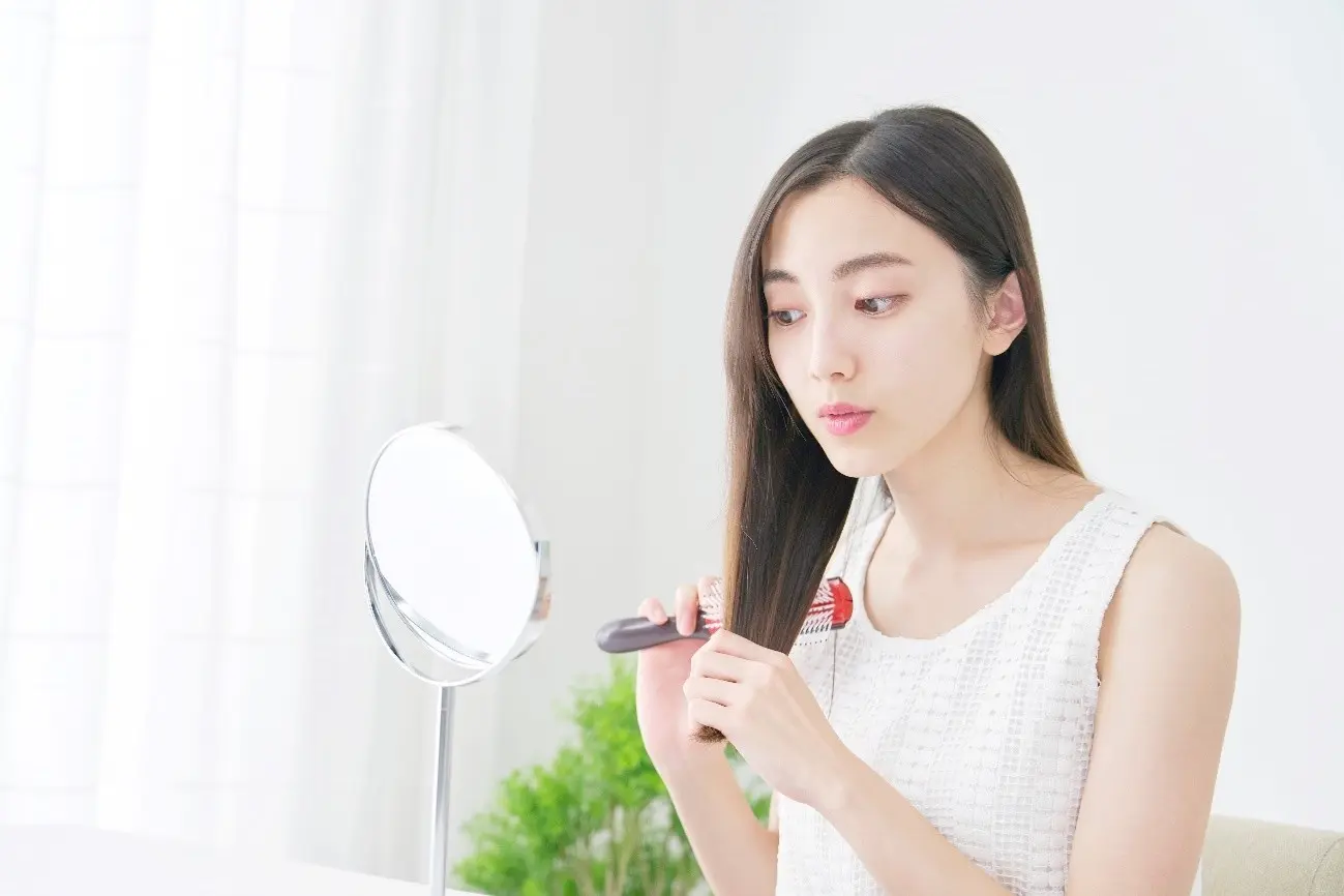 鏡を見ながら髪をとかす女性
