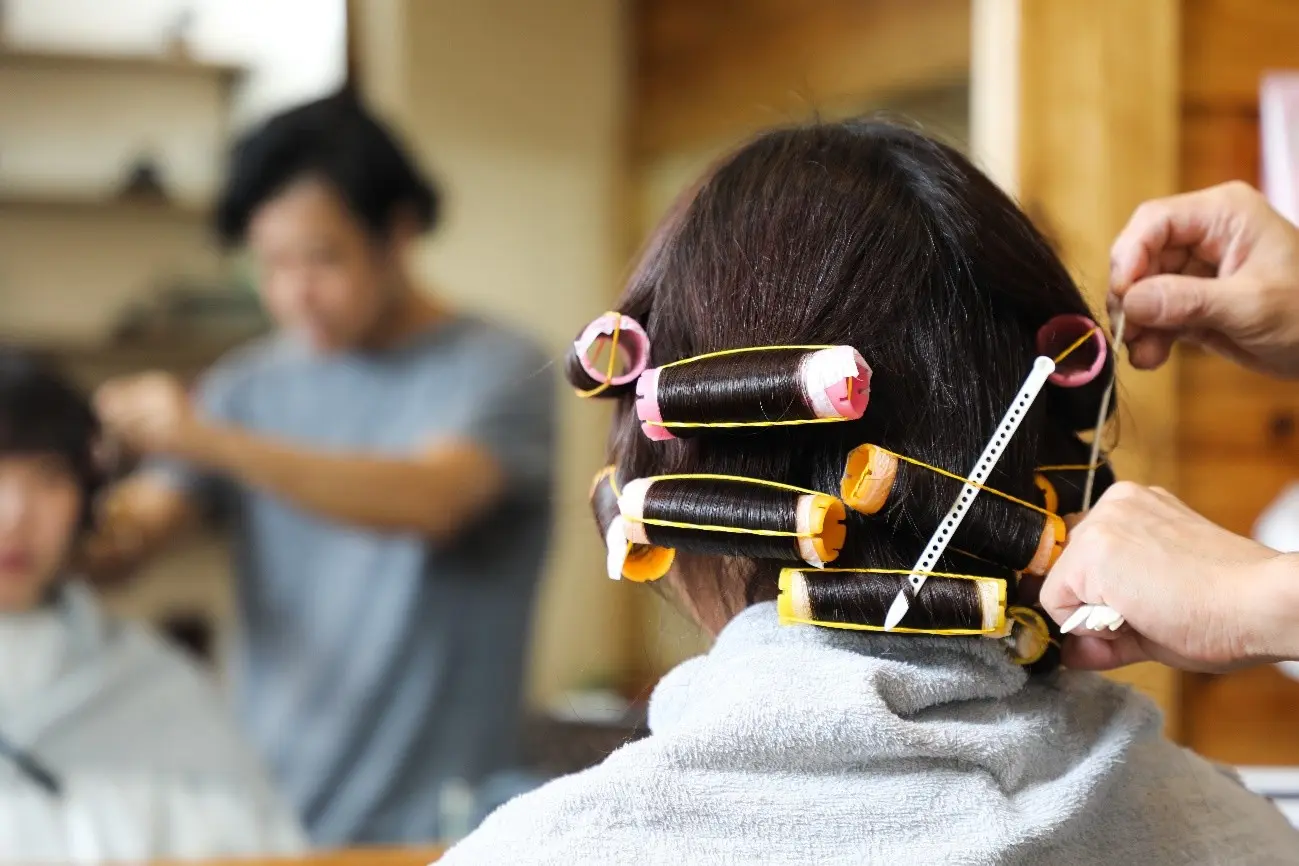 美容院でパーマの施術を受ける女性