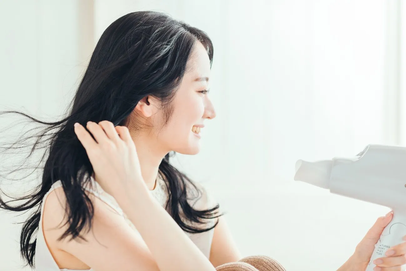 ドライヤーで髪を乾かす女性の横顔