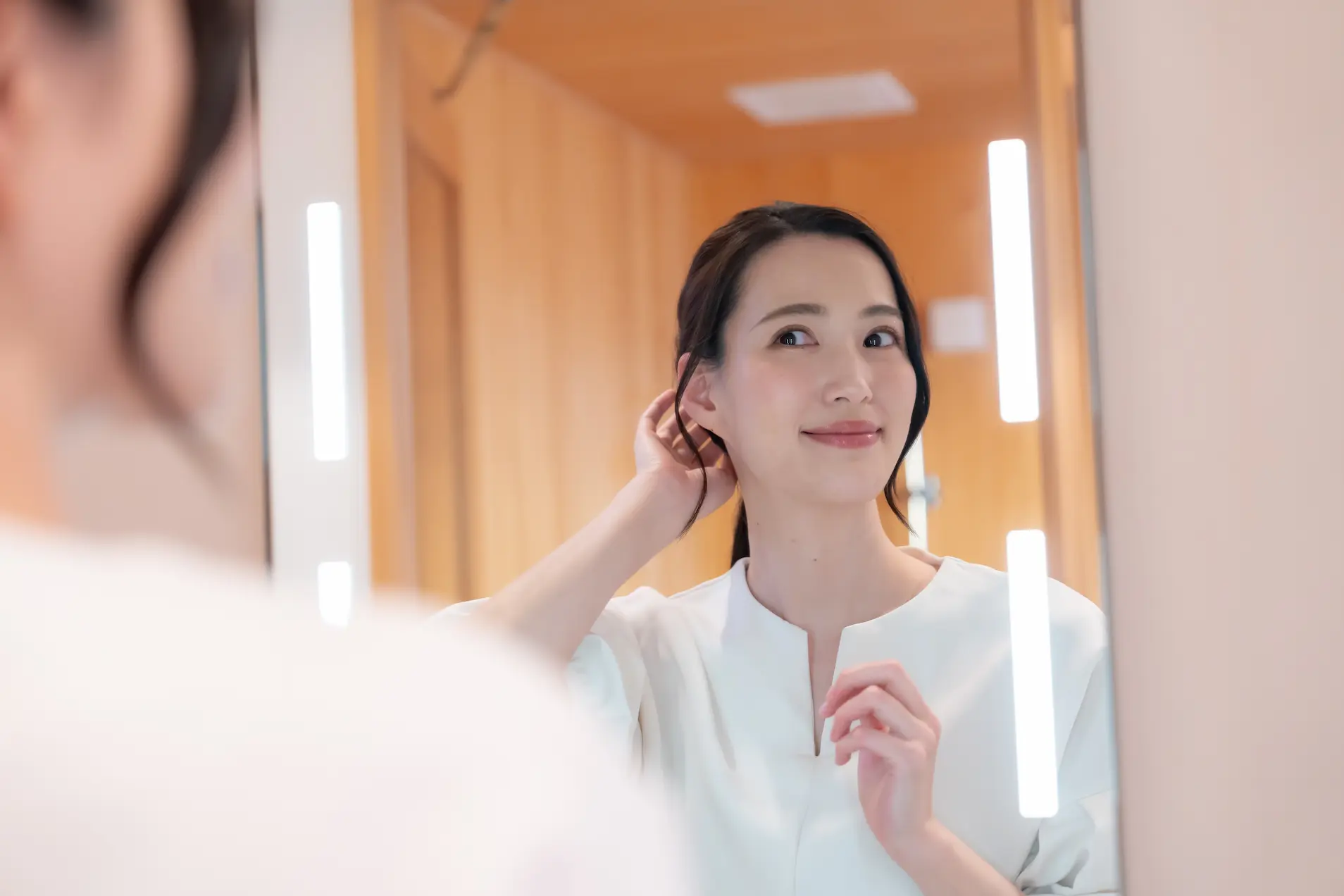 鏡で姿を確認する微笑む女性の画像