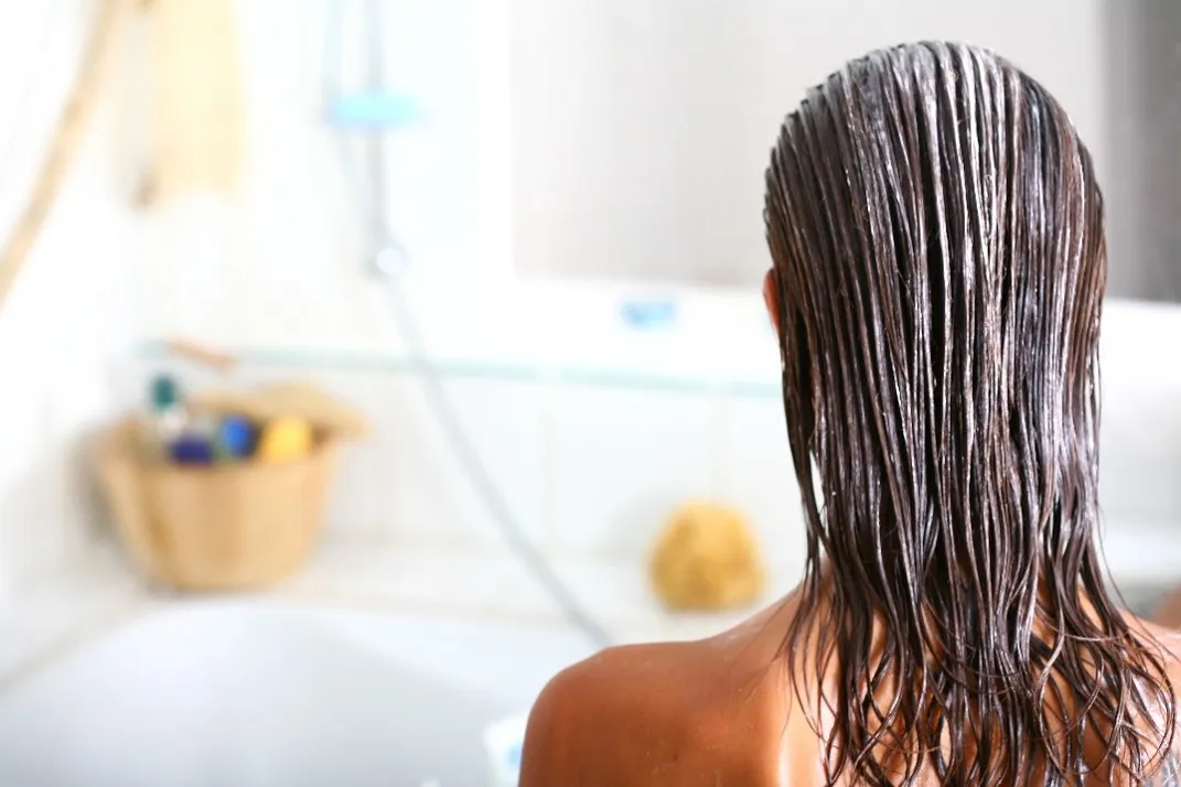 浴室でヘアケアをする女性の後ろ姿