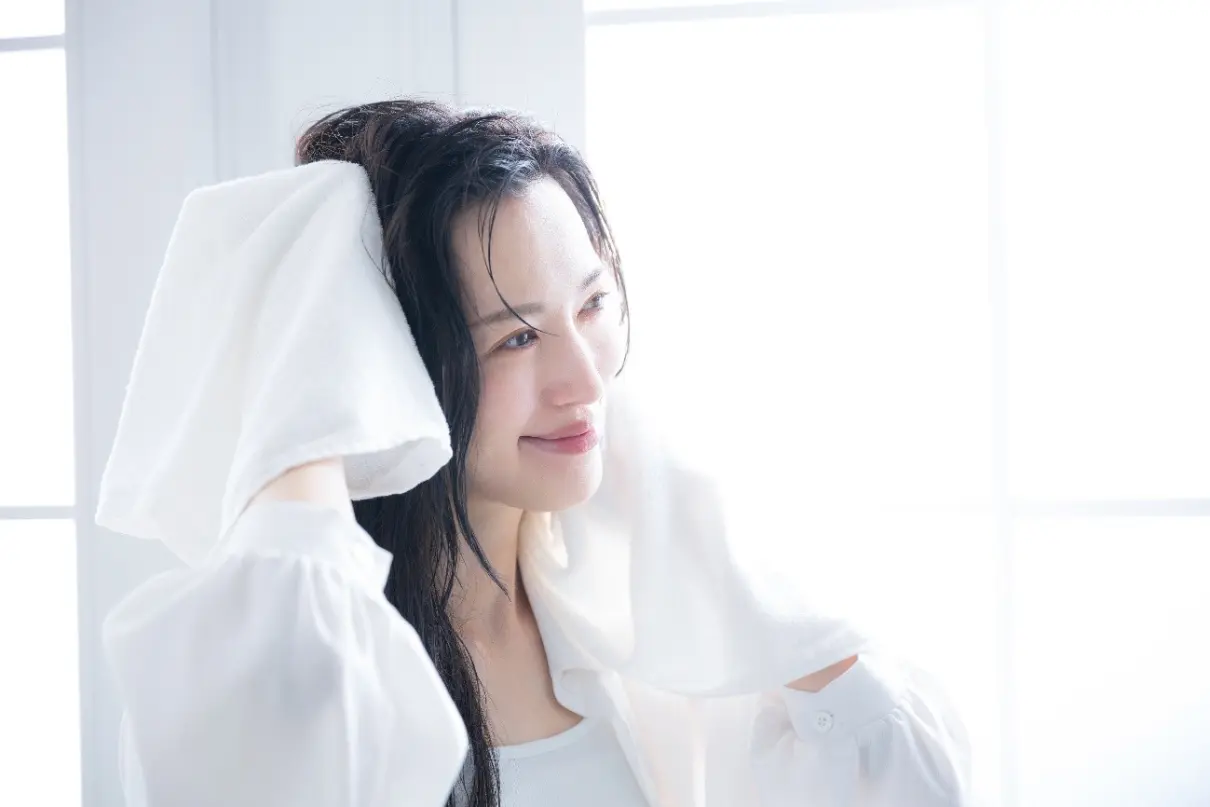 濡れた髪をタオルで拭く女性