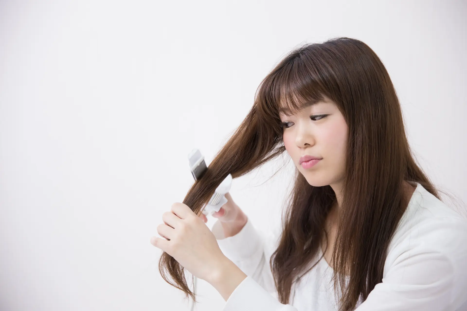 髪の毛にヘアアイロンを当てる女性
