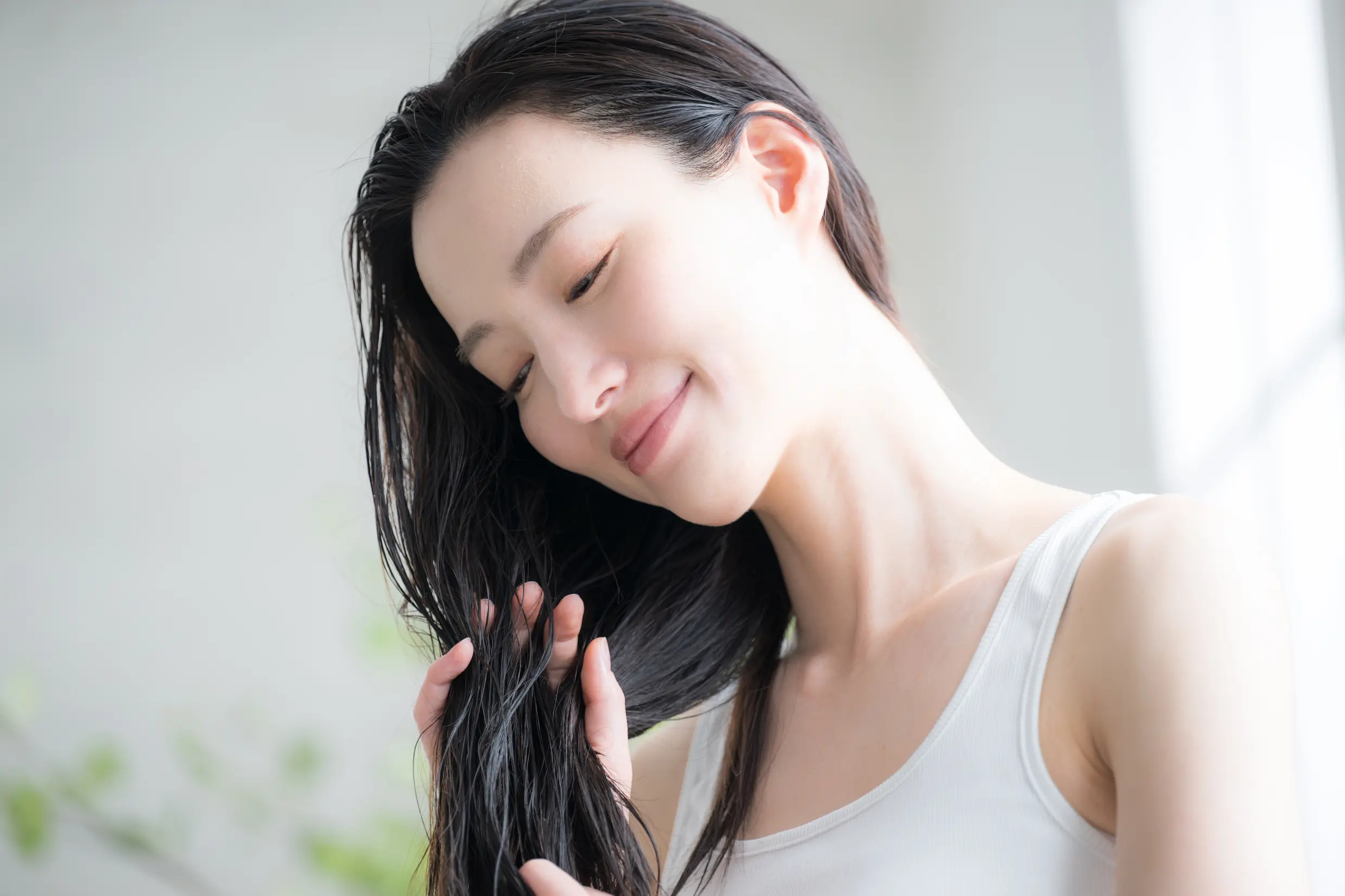 手でとかしている髪の毛を見つめる女性