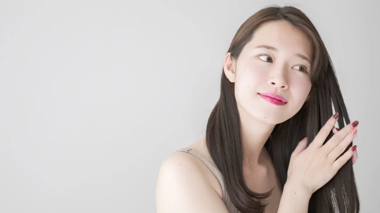 手のひらで髪を触る女性