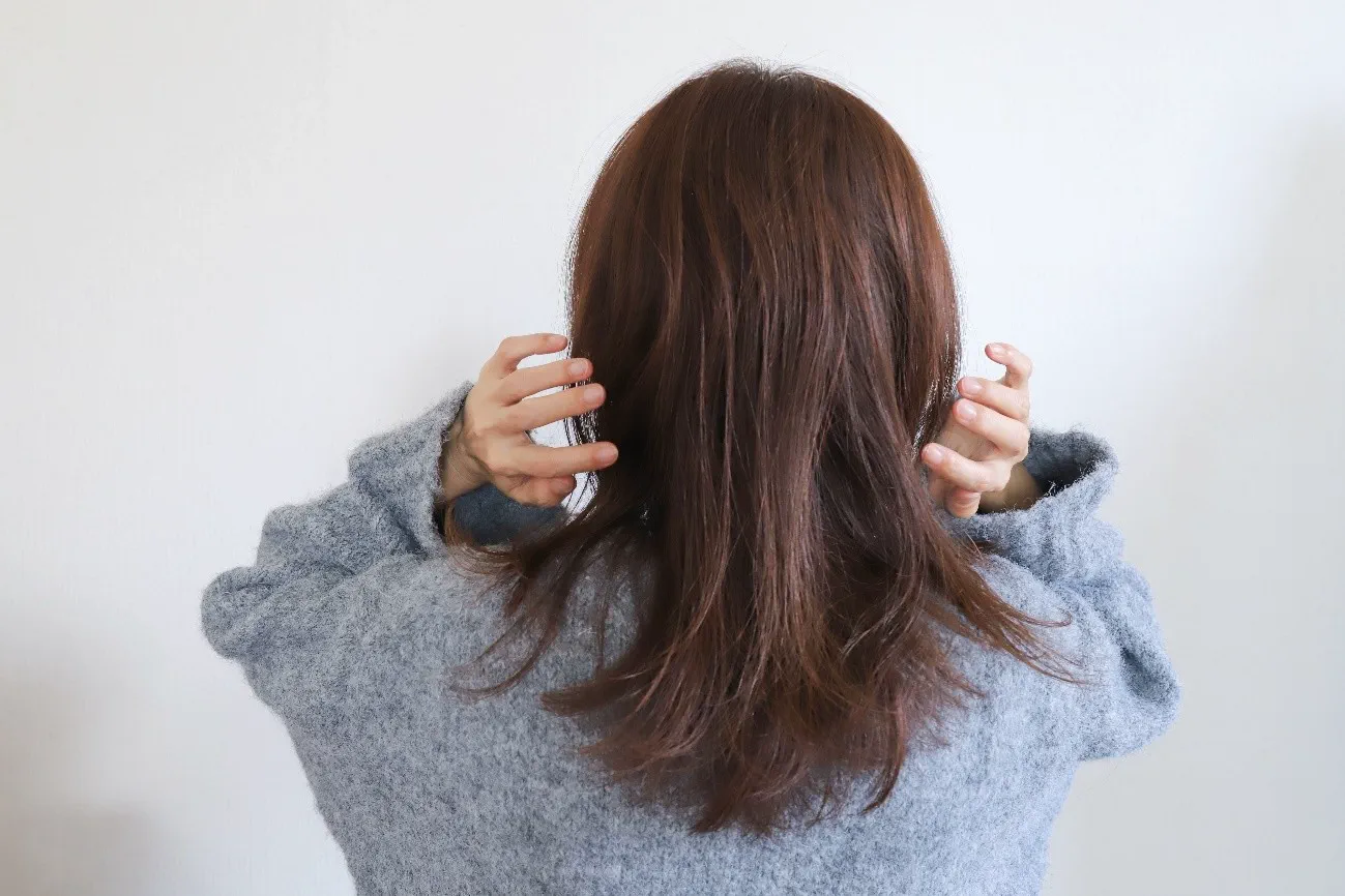 髪の毛に触れようとする女性の後ろ姿