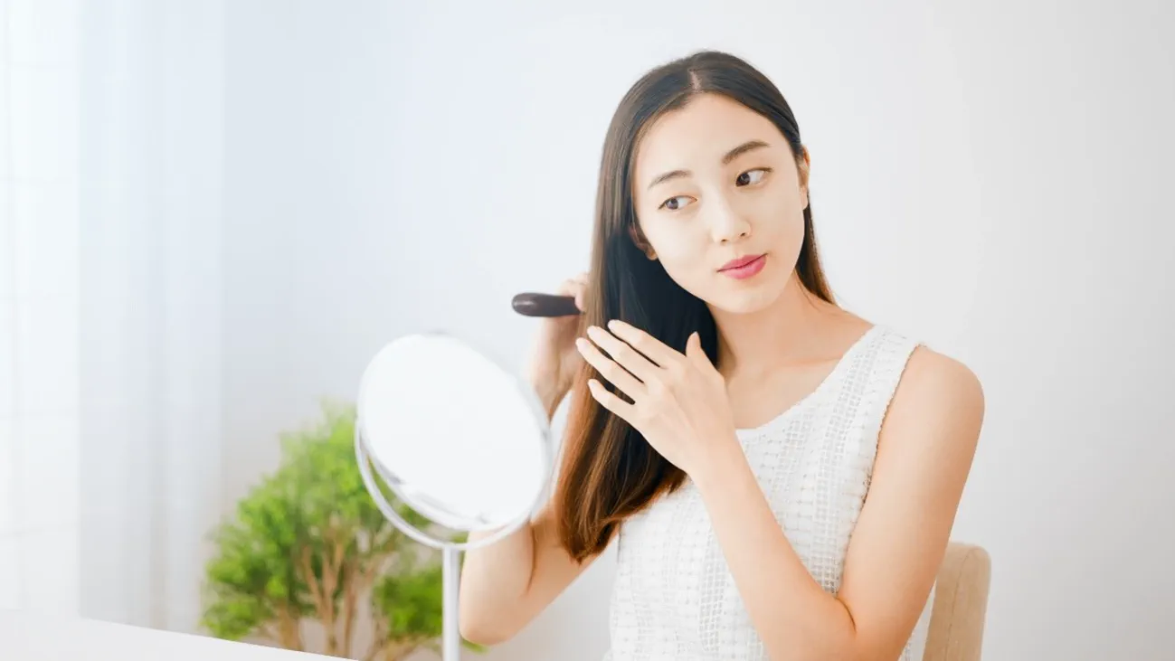 鏡を見ながら髪をとかす女性