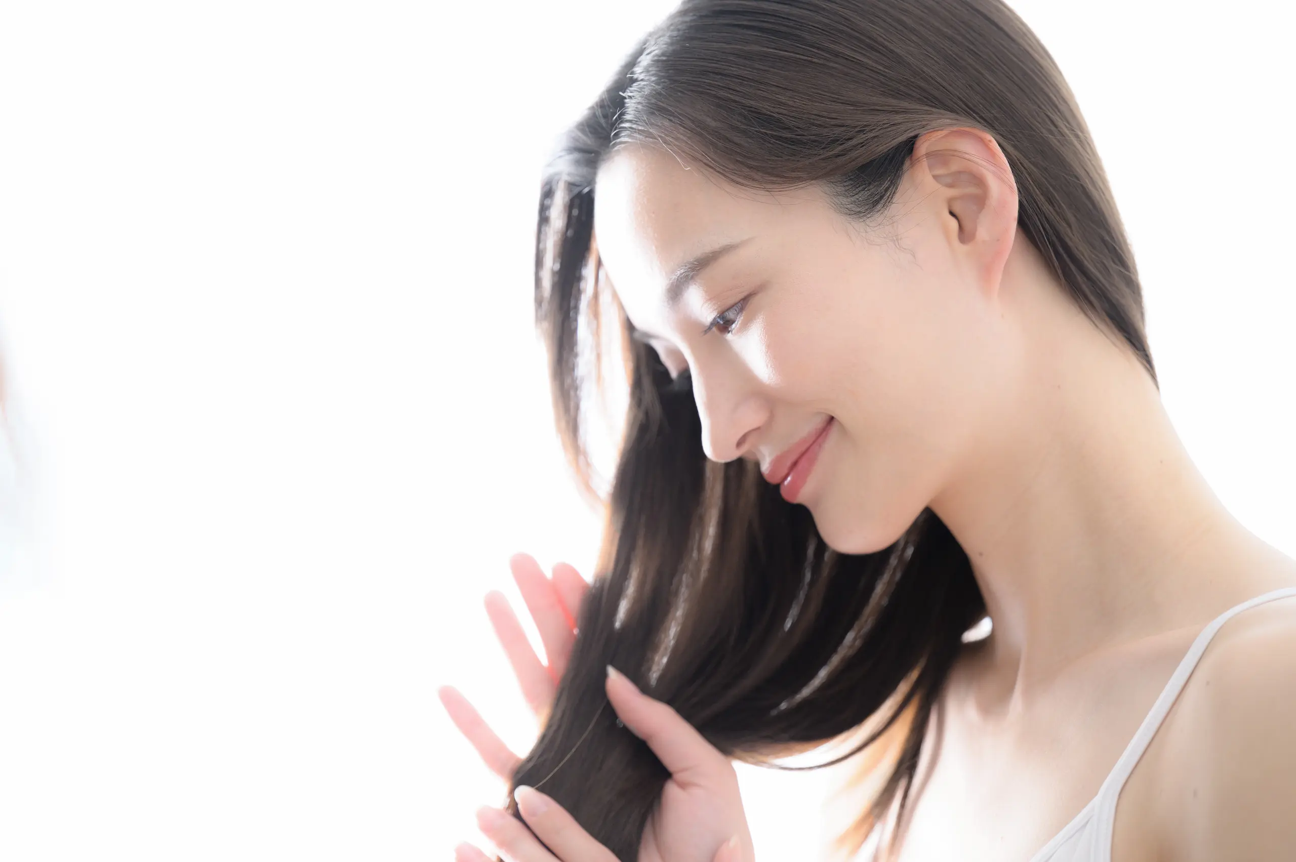 髪を見つめる女性の横顔の画像