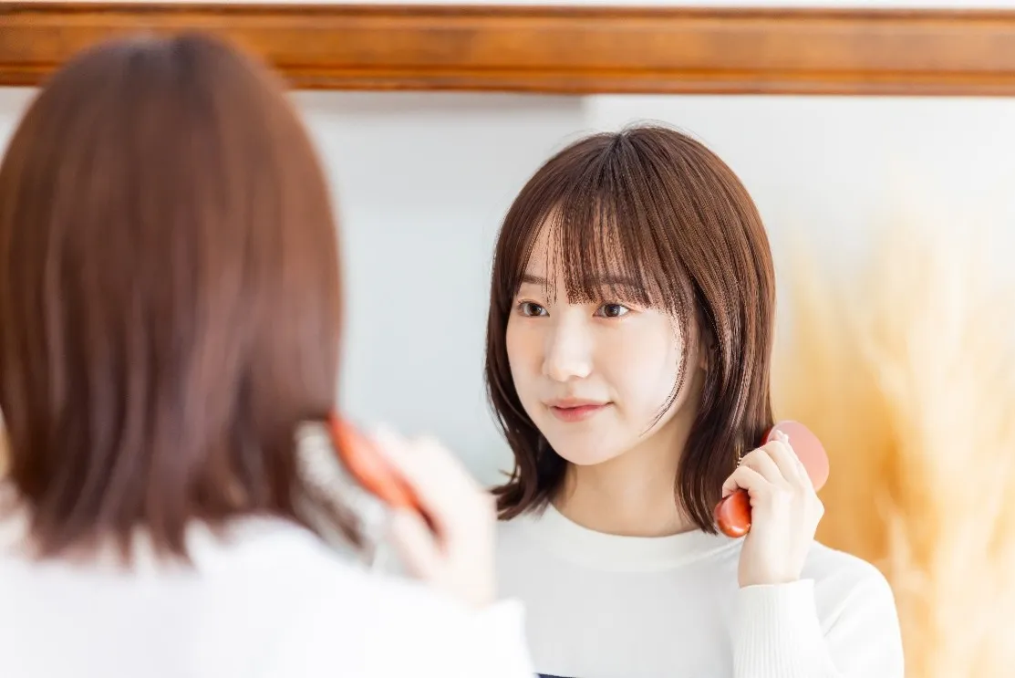 鏡を見ながら髪をとかす女性