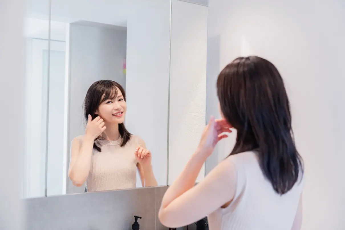 鏡を見ながらヘアセットをする女性