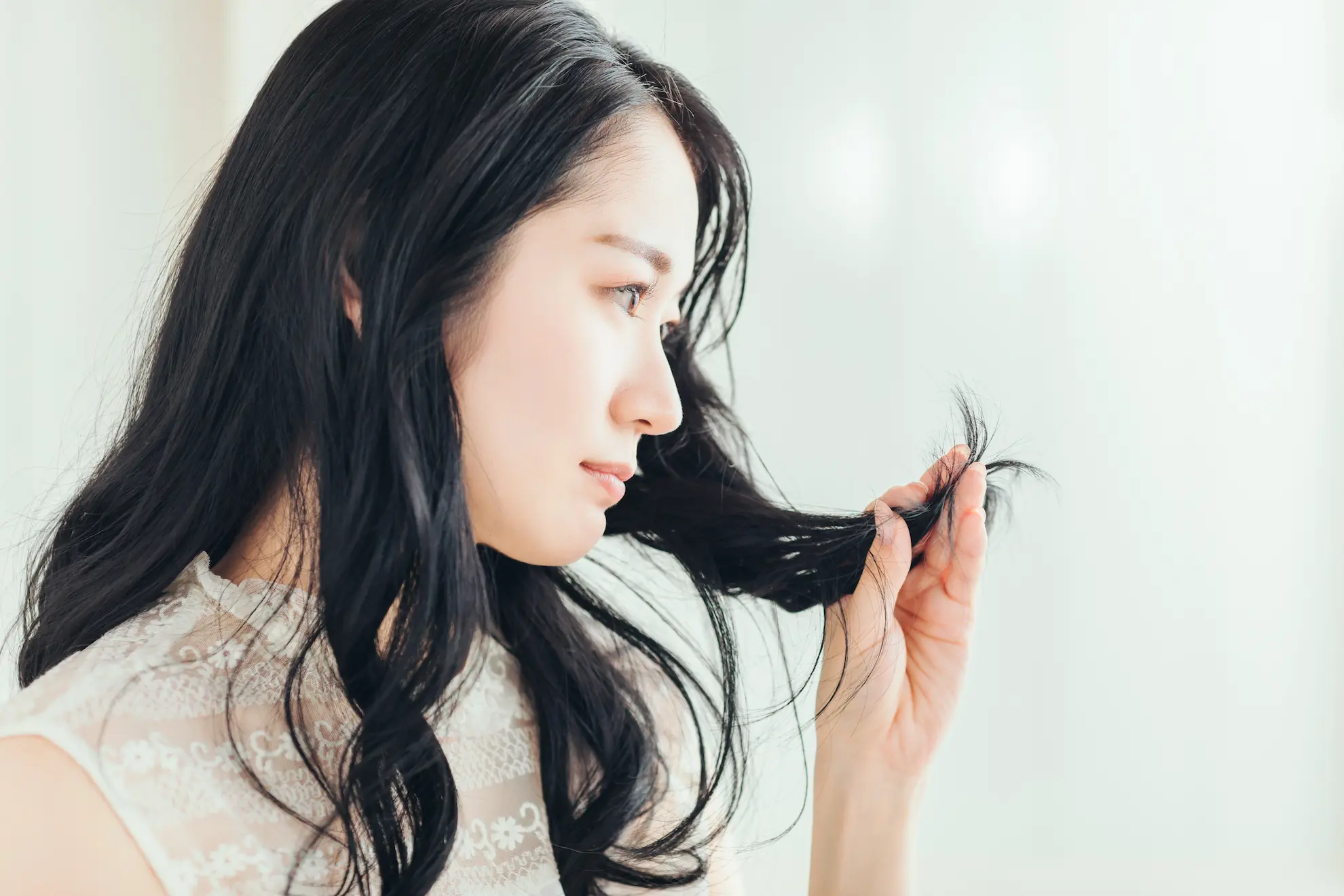 毛先を見つめる女性の横顔の写真