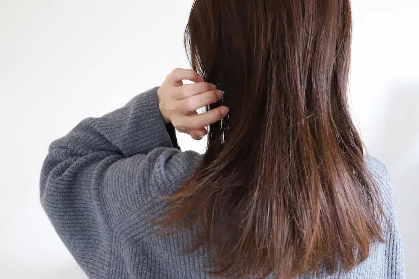 傷んだ髪の毛を触る女性の後ろ姿の画像