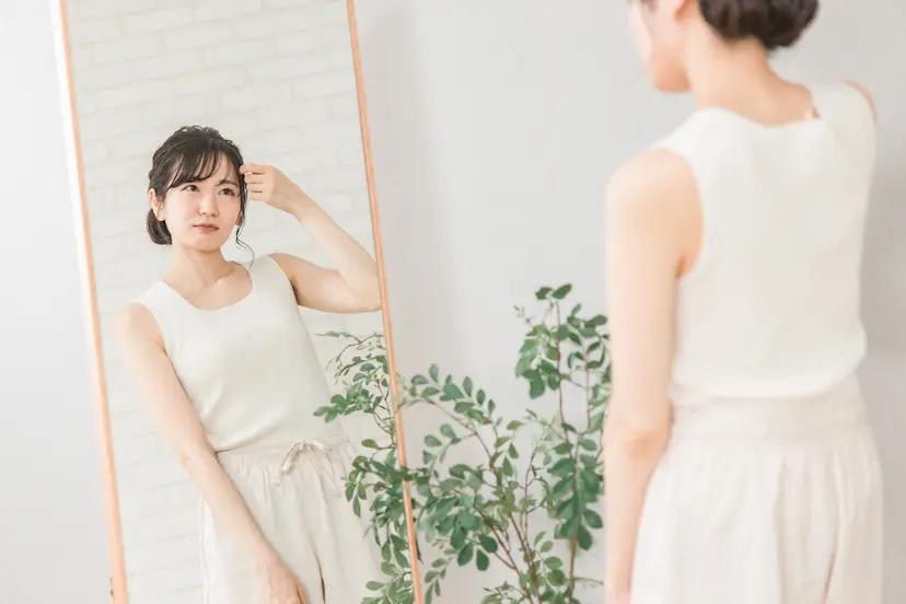 鏡の前で髪型を確認する女性の画像
