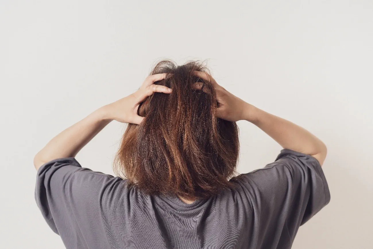 頭を抱える女性の後ろ姿