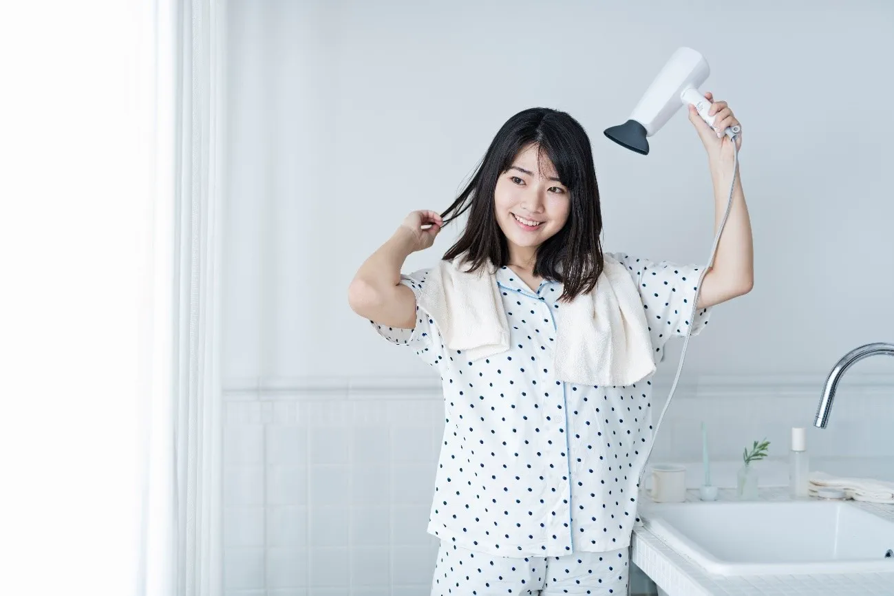 ドライヤーで髪を乾かす女性